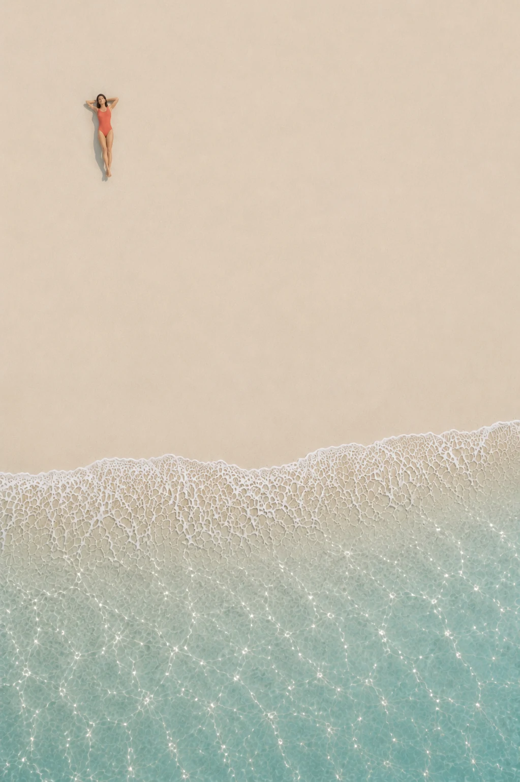 Aerial view of a woman lying on the beach beside the ocean